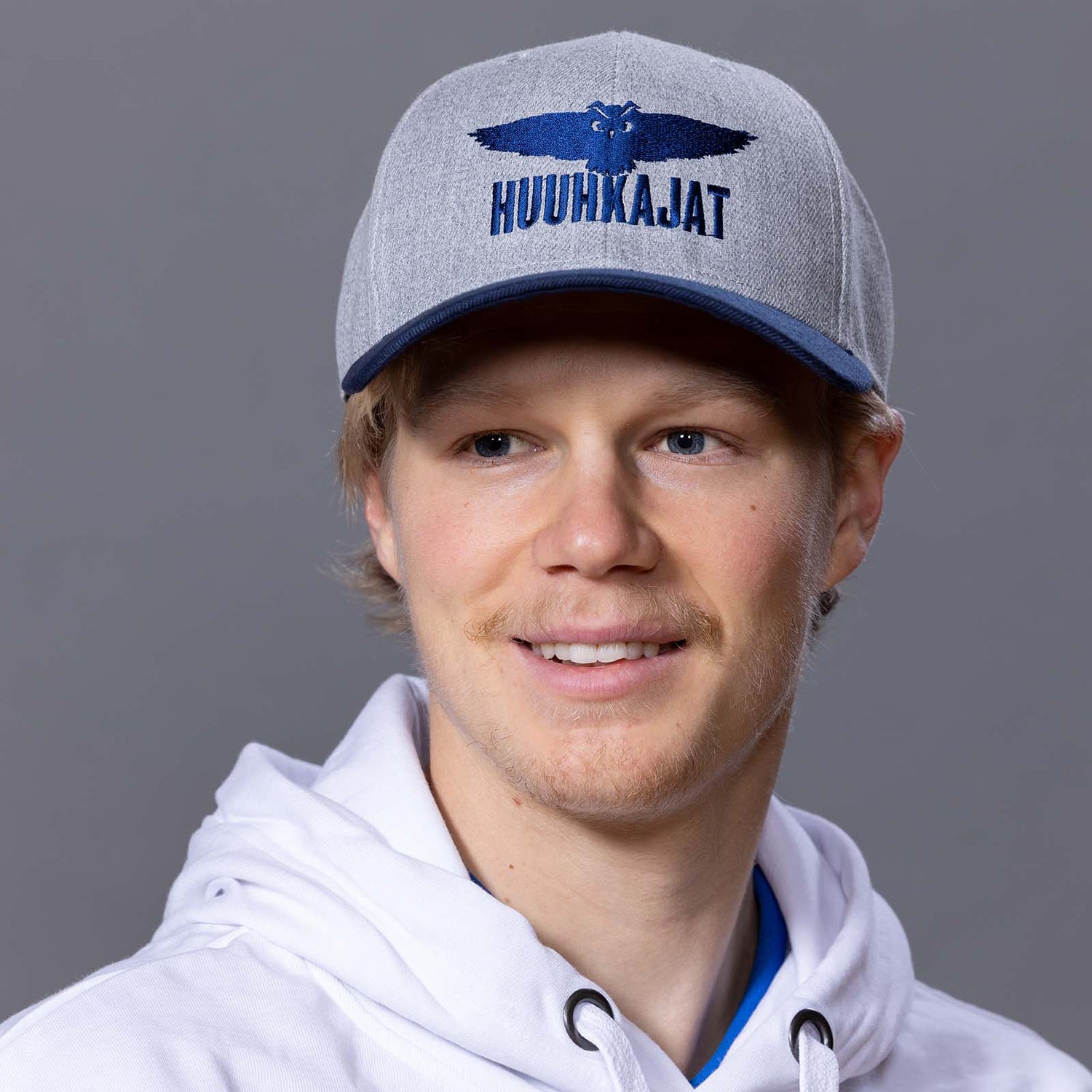 Harmaa lippis tummansinisellä lipalla ja Huuhkajat-logolla.